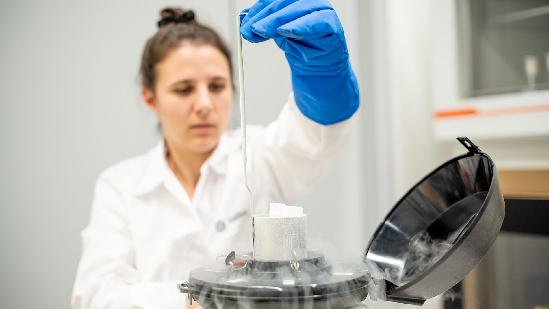 Wissenschaftlerin arbeitet mit Kältegerät im Labor