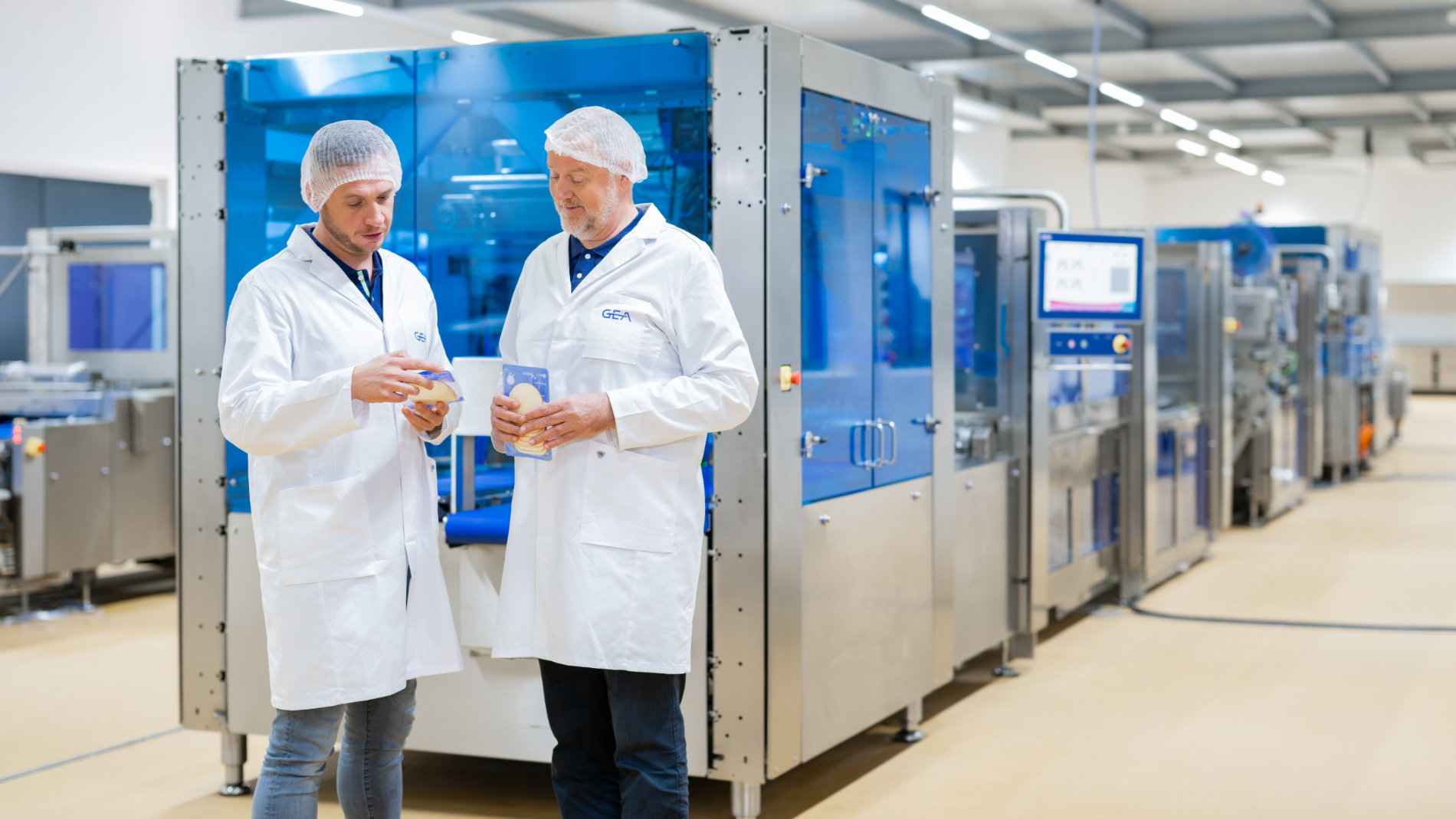 Zwei Mitarbeiter inspizieren Produkte vor einer Maschine.