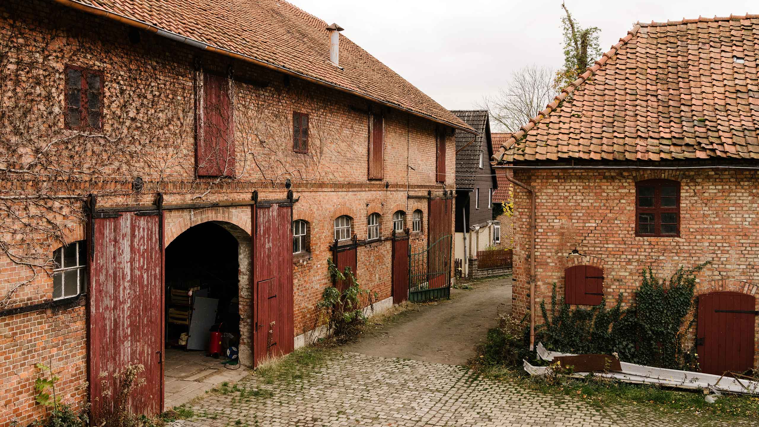 Entrance of old farmhouse with red brick walls and gates