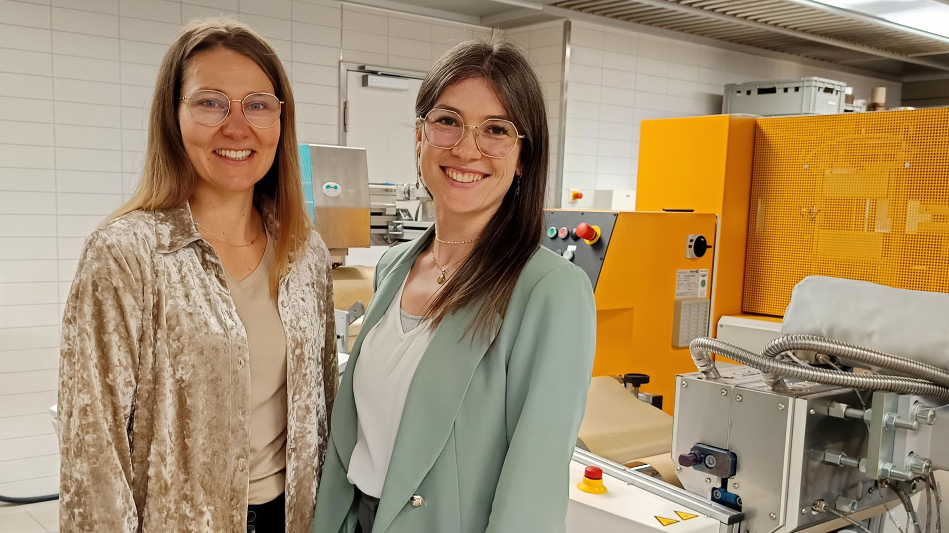 Mara Strenger und Alina Siebler in Produktionshalle vor einer Verpackungsmaschine