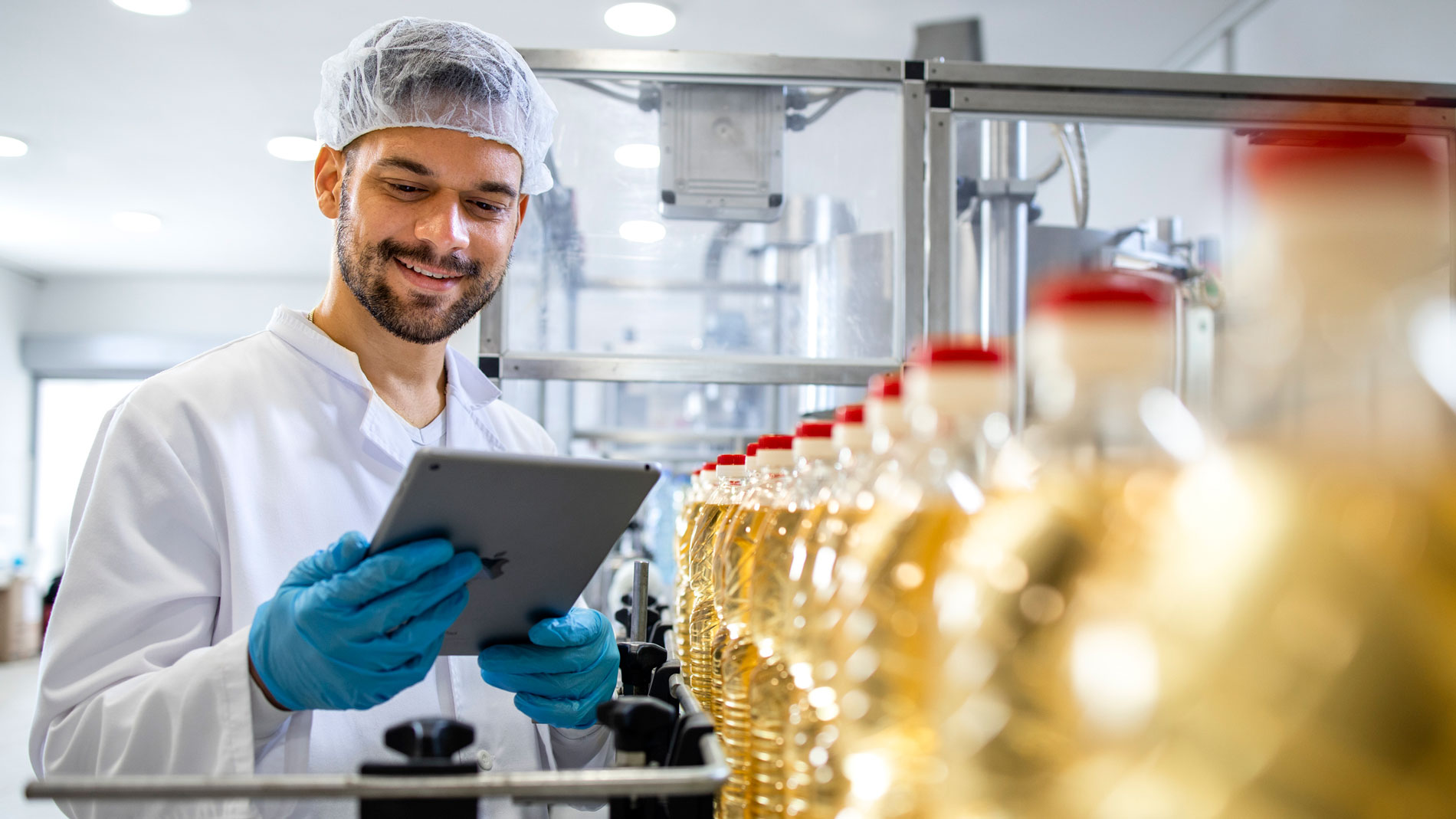 Employee in food production monitoring a filling line with a tablet