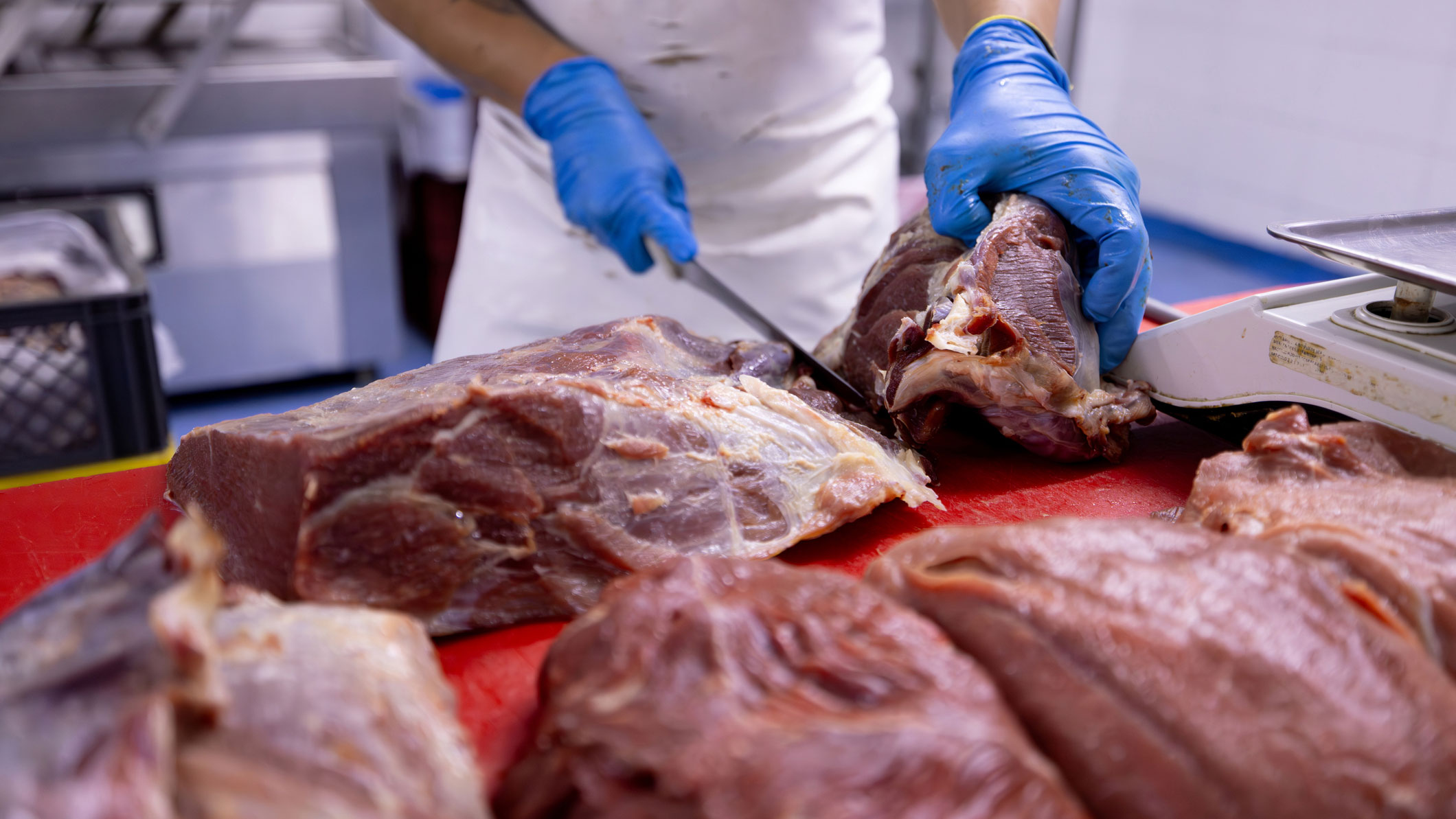Butcher cutting meat on a red worktable