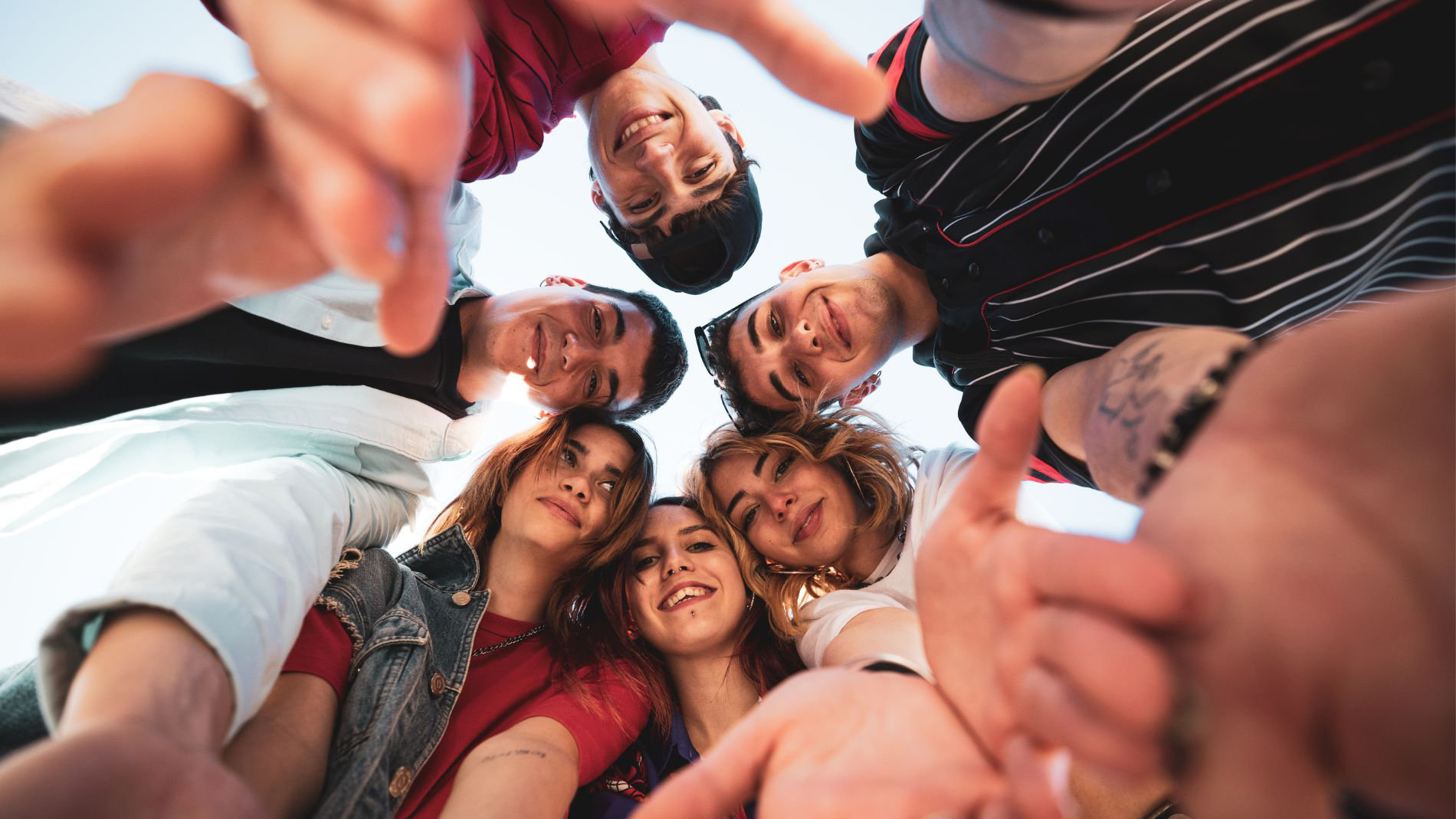 Young people in a circle are photographed from below.