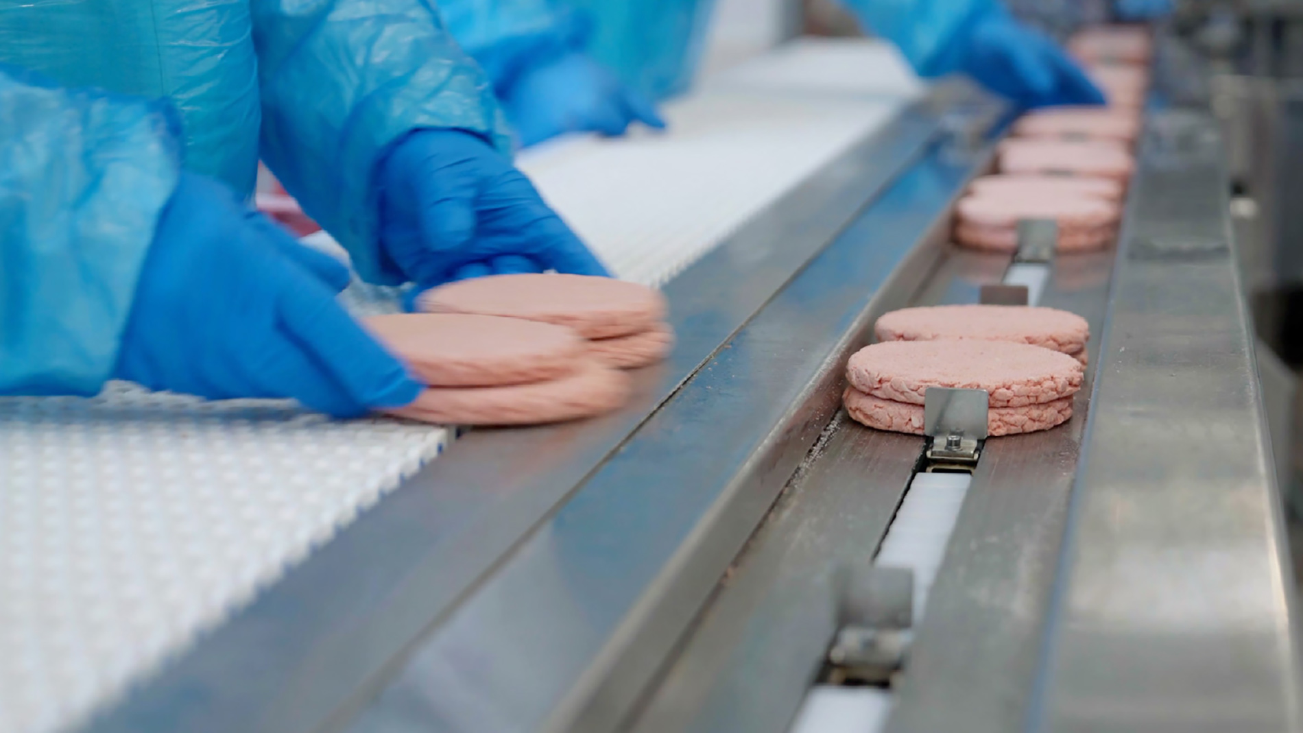 Meat patties sorted on conveyor with gloves