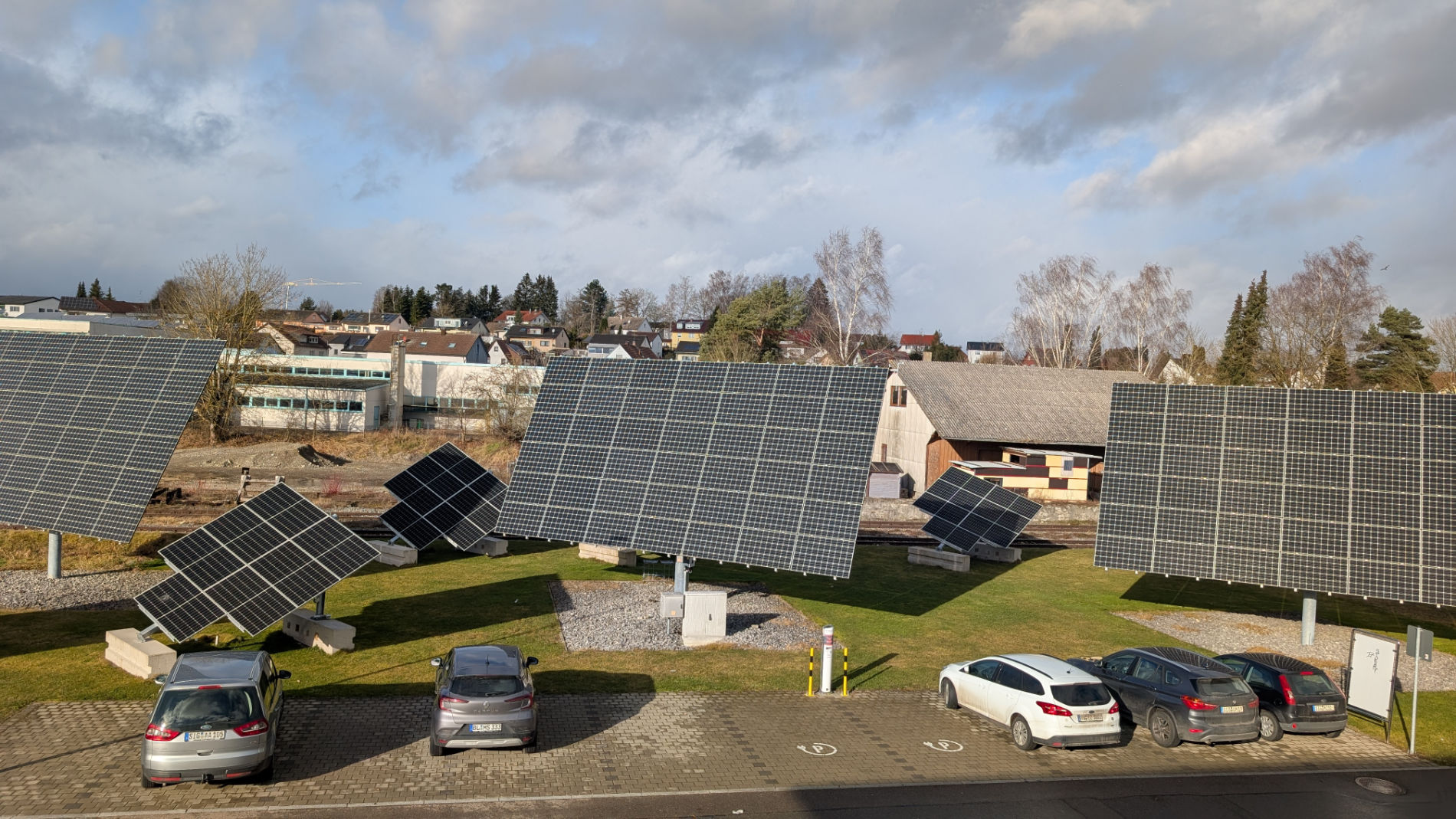 Solaranlage neben geparkten Autos und Gebäuden
