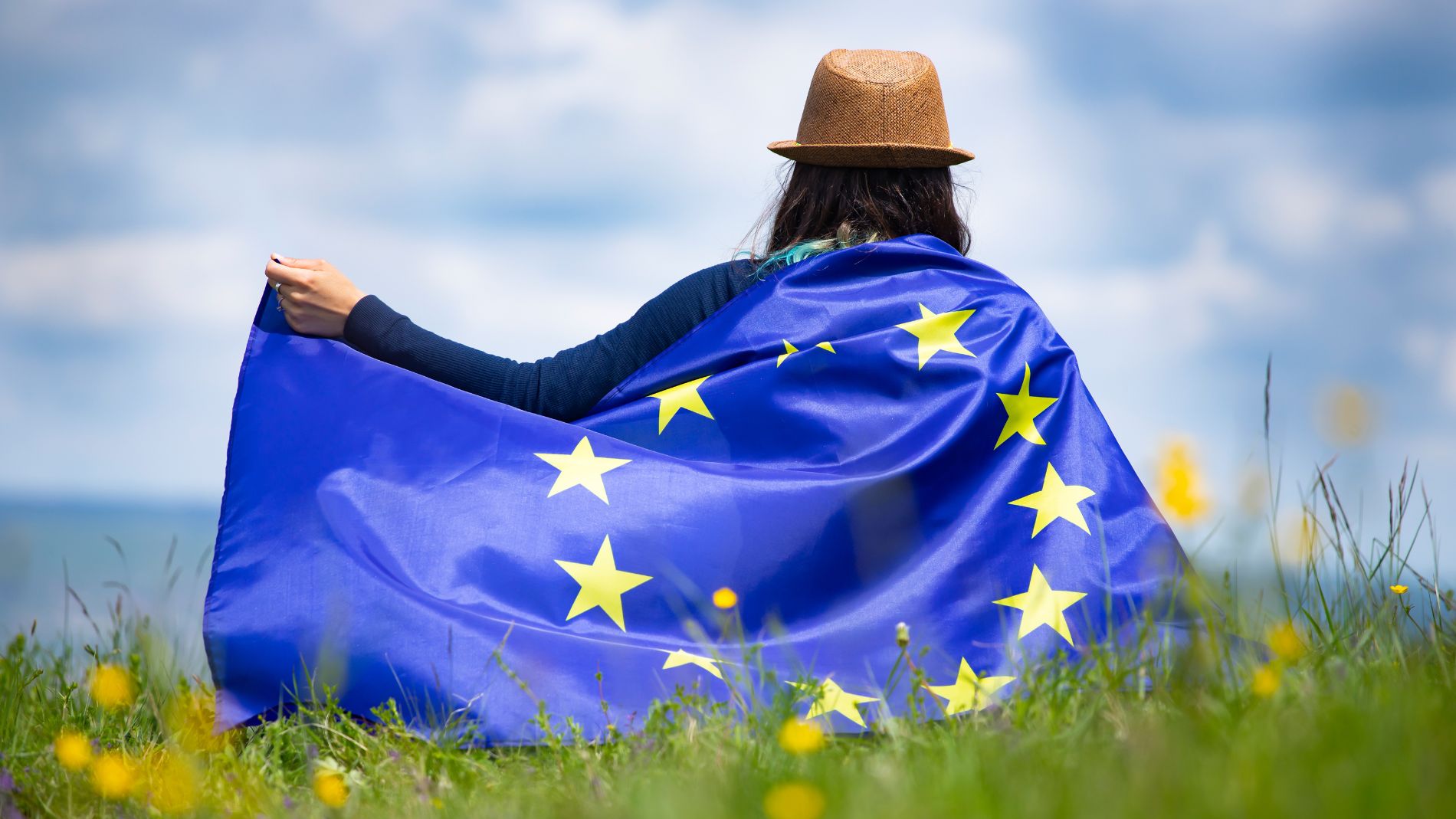 Frau mit EU-Flagge sitzt auf einer Wiese