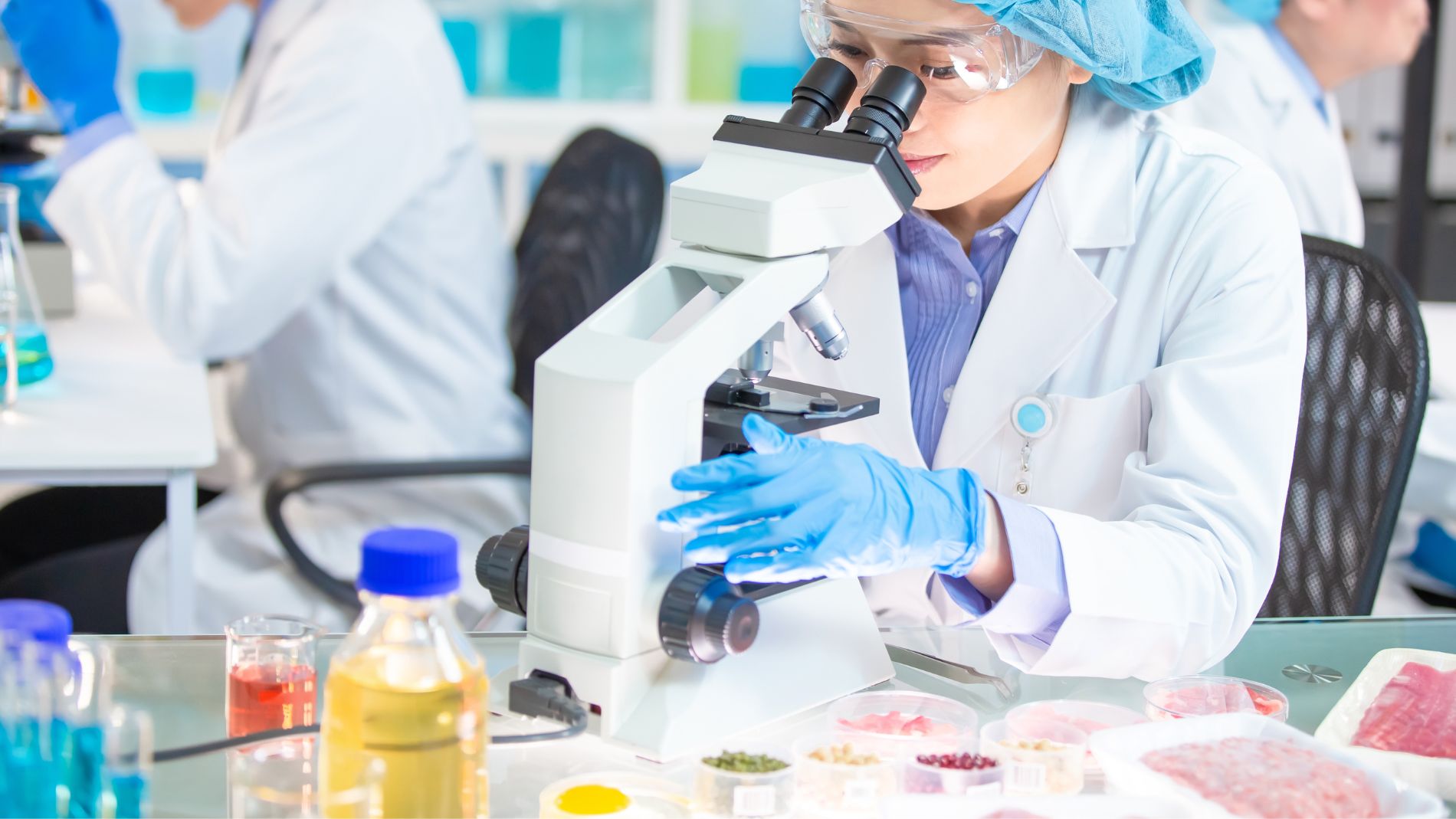 Lab technician analysing meat samples under microscope